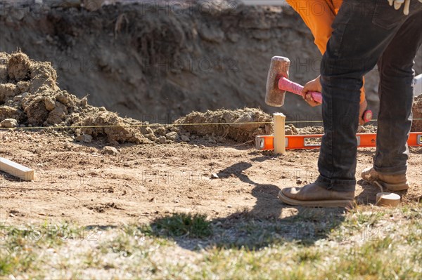 Worker installing stakes and lumber guides at construction site