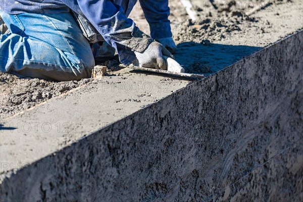 Pool construction worker working with wood float on wet concrete