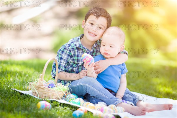 mixed-race chinese and caucasian boys outside in park playing with easter eggs