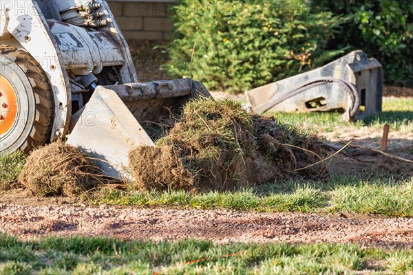 Small bulldozer removing grass from yard preparing for pool installation