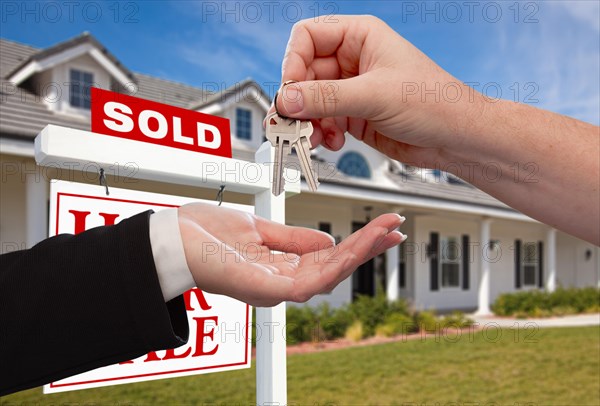 Handing over the house keys in front of sold new home against a blue sky