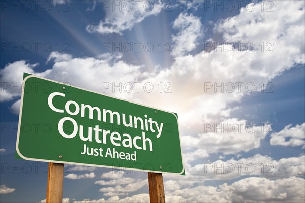 Community outreach green road sign with dramatic clouds and sky