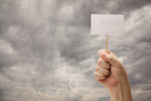 Man holding blank sign over dramatic storm cloudy sky