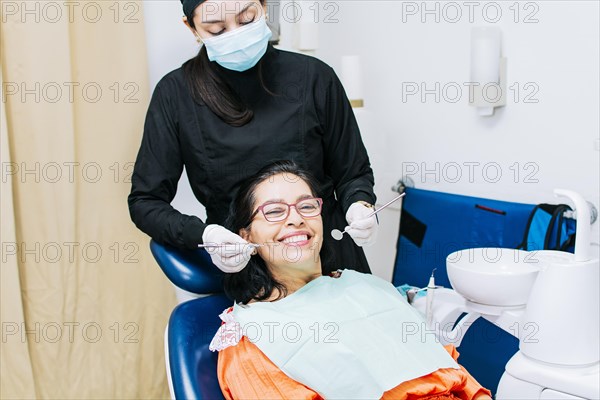 Dentist examining mouth to smiling patient