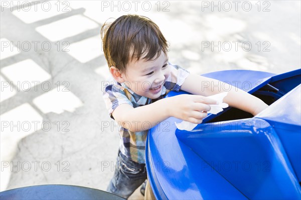 Happy cute mixed-race boy placing paper into the recycle bin