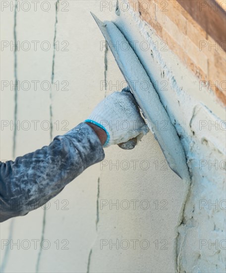 Worker smoothing wet pool plaster with trowel