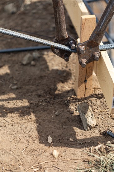 Worker using tools to bend steel rebar at construction site