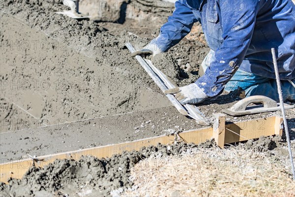 Pool construction worker working with A smoother rod on wet concrete