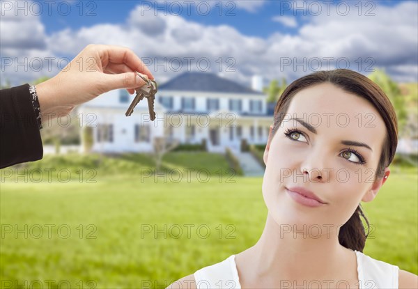 Real estate agent hands thoughtful pretty mixed-race woman keys in front of house