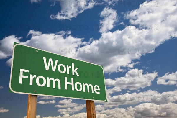 Work from home green road sign with dramatic clouds and sky