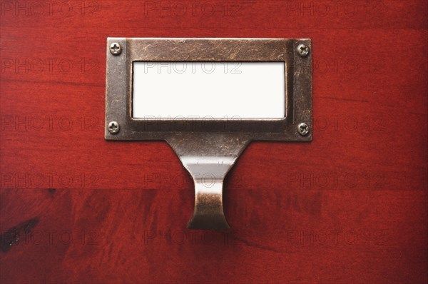 Lustrous wooden cabinet with blank file label in dramatic light