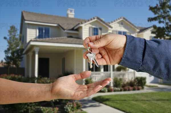 Handing over the house keys in front of a beautiful new home