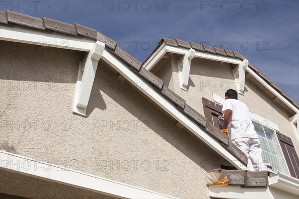 Busy house painter painting the trim and shutters of A home