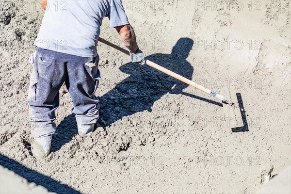 Pool construction worker working with A bullfloat on wet concrete