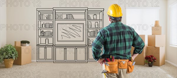 Contractor inside room with boxes facing entertainment unit drawing on wall