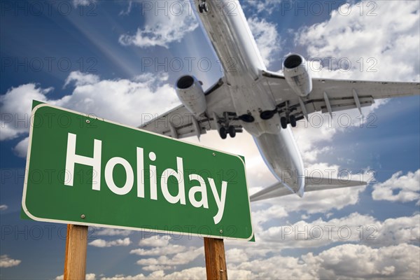 Holiday green road sign and airplane above with dramatic blue sky and clouds