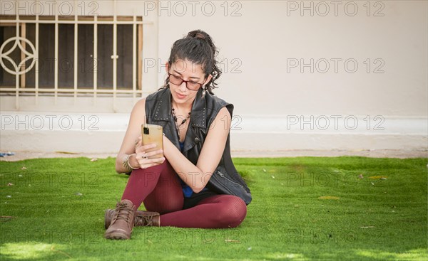 Girl sitting on the grass checking her cell phone
