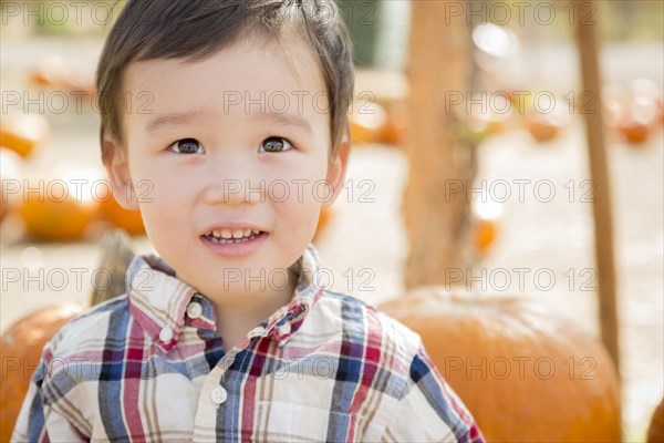 Cute mixed-race young boy having fun at the pumpkin patch