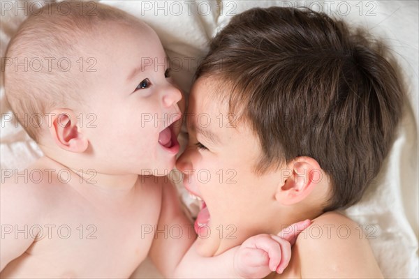 Young mixed-race chinese and caucasian baby brothers having fun on their blanket