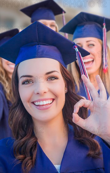 Happy graduating group of girls in cap and gown celebrating on campus