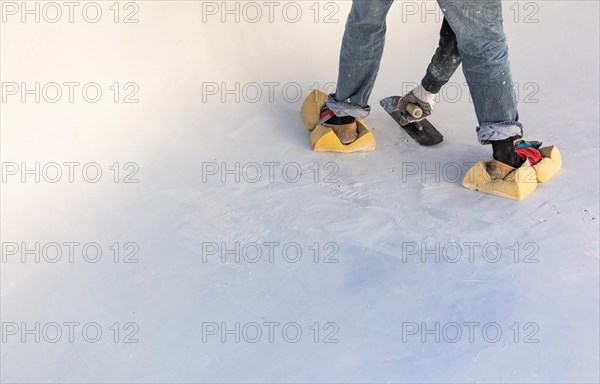 Worker wearing sponges on shoes smoothing wet pool plaster with trowel