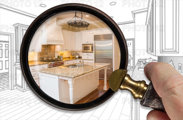 Hand holding magnifying glass revealing finished kitchen build over drawing