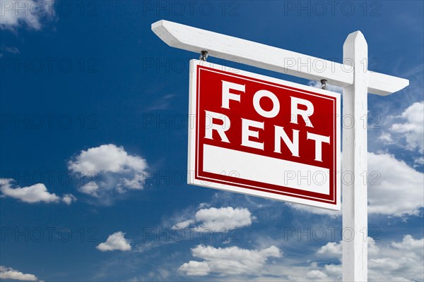 Left facing for rent real estate sign over blue sky and clouds with room for your text