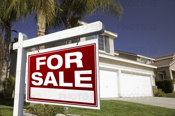 For sale real estate sign in front of house