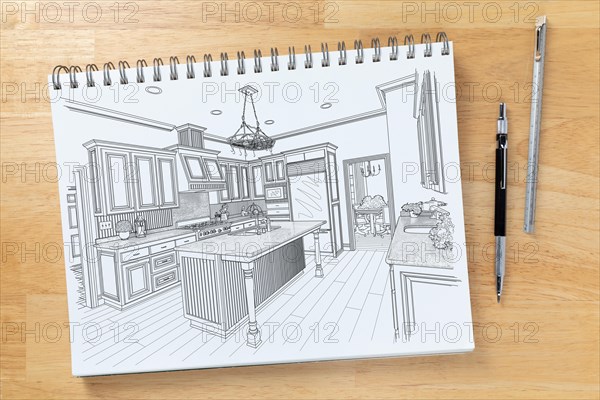 Sketch pad on desk top with drawing of custom kitchen interior next to engineering pencil and ruler scale