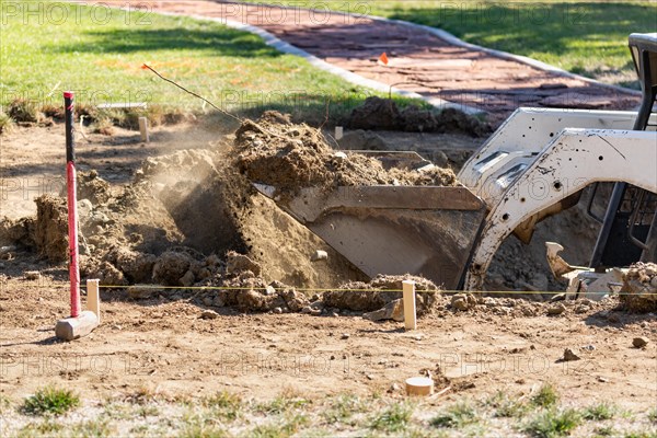 Small bulldozer digging in yard for pool installation