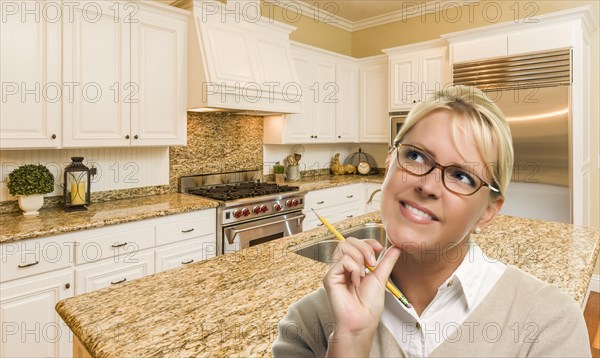 Attractive daydreaming woman with pencil inside beautiful custom kitchen