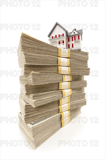 Small house on stacks of hundred dollar bills isolated on a white background