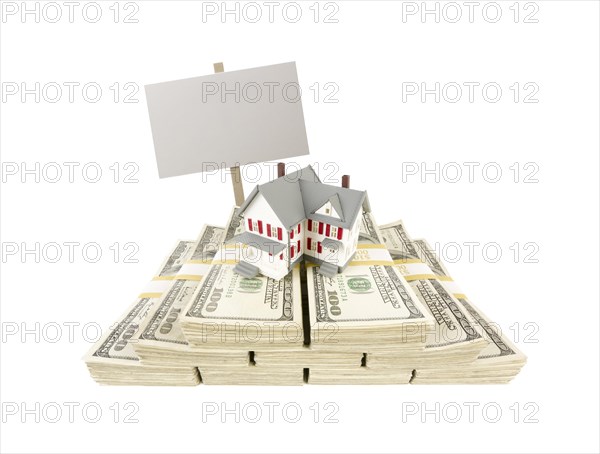 Small house on stacks of hundred dollar bills and blank sign isolated on a white background