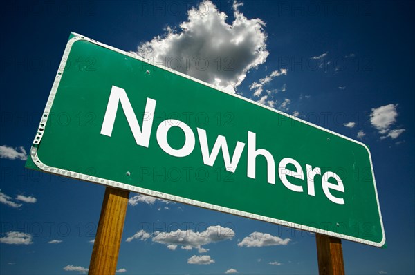 Nowhere green road sign against dramatic blue sky and clouds