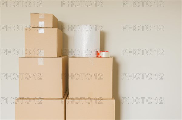 Variety of packed moving boxes with materials in empty room against wall