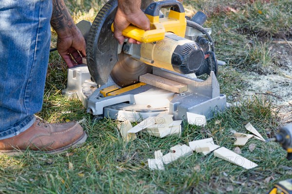 Worker using electric miter saw at constrcution site