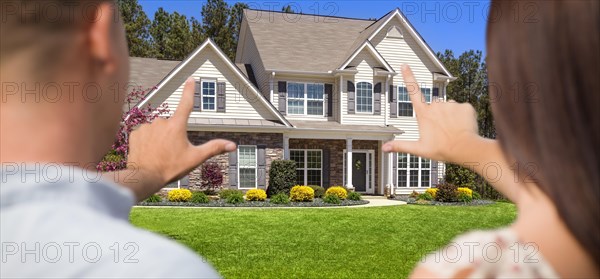 House and military couple framing hands in front yard