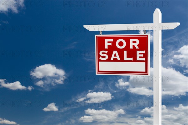 Left facing for sale real estate sign over blue sky and clouds with room for your text