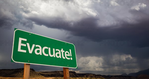 Evacuate green road sign with dramatic clouds and rain