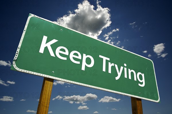 Keep trying road sign with dramatic clouds and sky