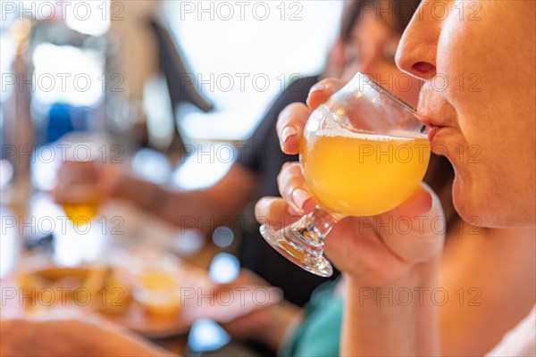 Female sipping glass of micro brew beer at bar with friends