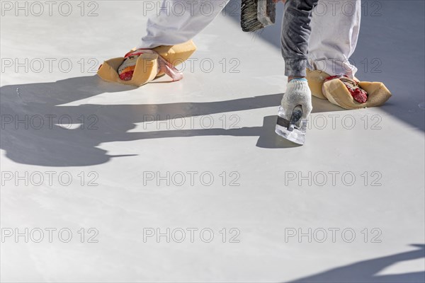 Worker wearing sponges on shoes smoothing wet pool plaster with trowel