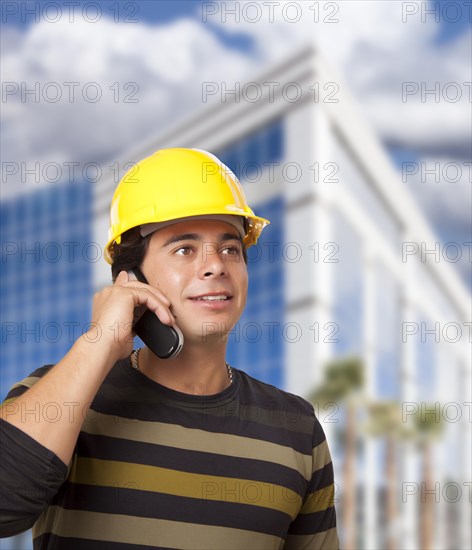 Handsome hispanic male contractor on cell phone in front of corporate building