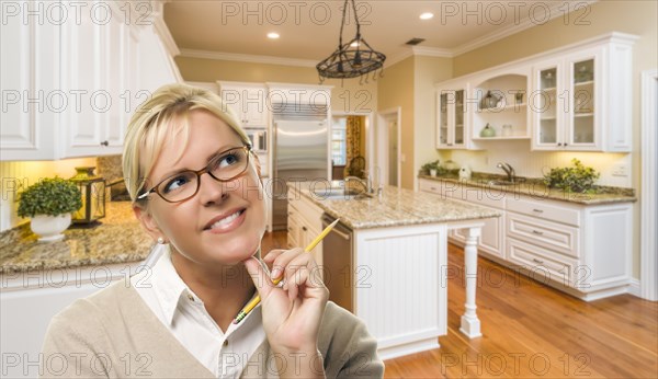 Attractive daydreaming woman with pencil inside beautiful custom kitchen