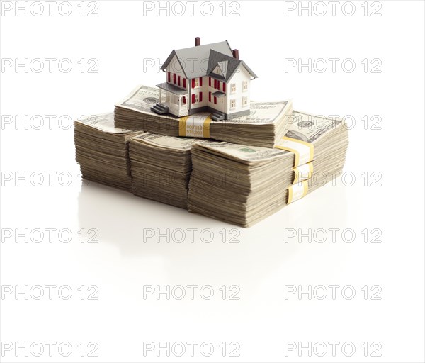 Small house on stacks of hundred dollar bills isolated on a white background