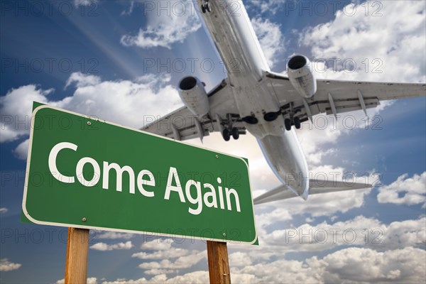 Come again green road sign and airplane above with dramatic blue sky and clouds