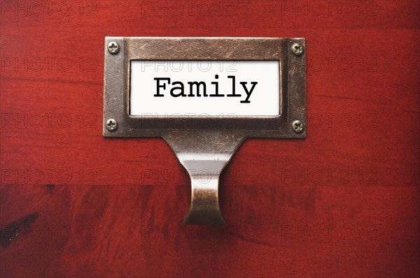 Lustrous wooden cabinet with family file label in dramatic light