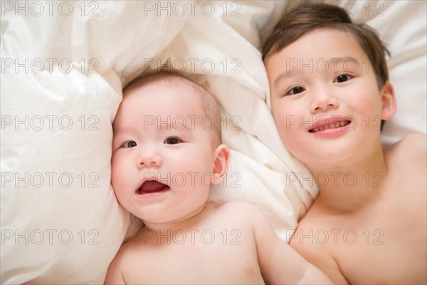 Young mixed-race chinese and caucasian baby brothers having fun on their blanket