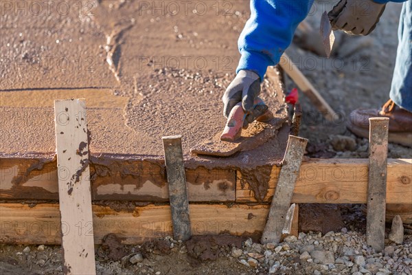 Construction worker smoothing wet cement with trowel tools