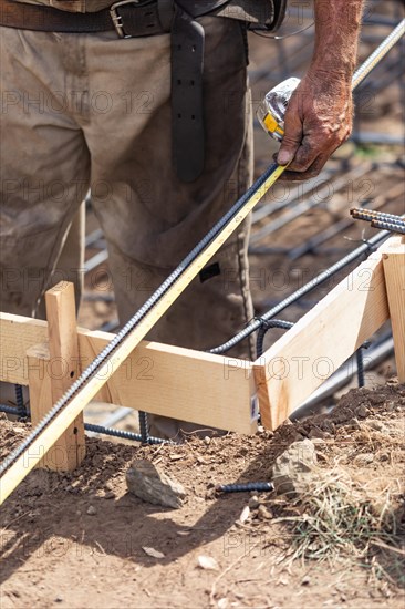 Worker measuring steel rebar at construction site